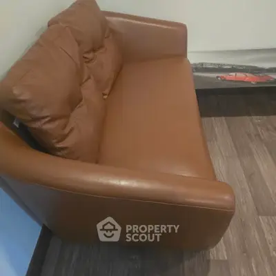 Stylish brown leather sofa in modern living room with wooden flooring.