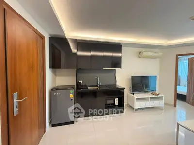 Modern studio apartment with sleek kitchen and cozy living area, featuring glossy cabinets and integrated appliances.