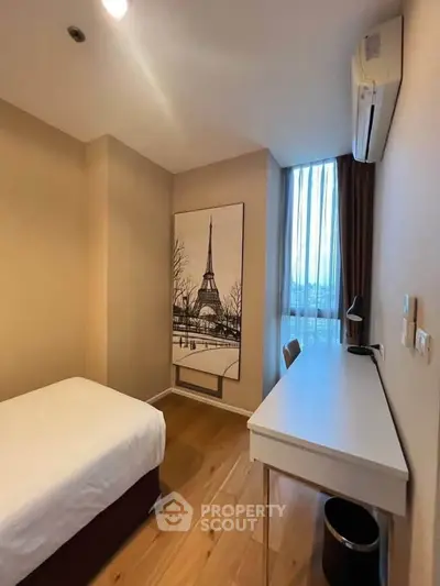 Cozy bedroom with wooden flooring, desk, and Eiffel Tower artwork, perfect for a serene living experience.
