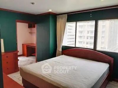 Spacious bedroom with large windows and built-in storage in urban apartment