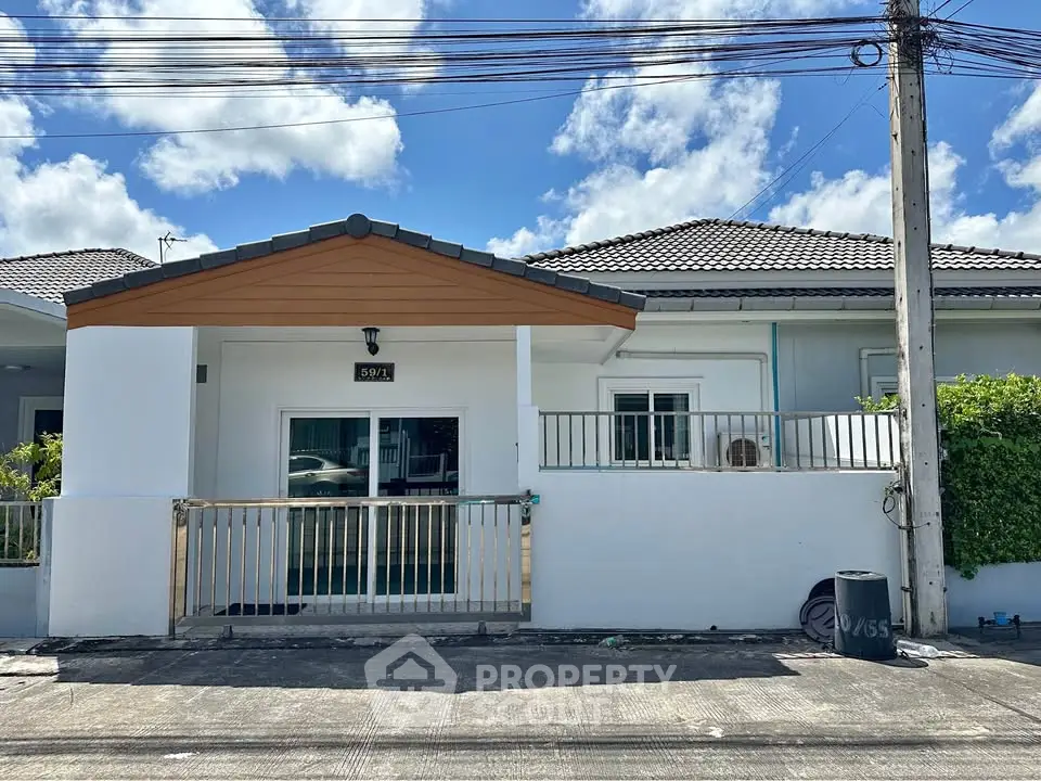 Charming single-story house with a modern facade and gated entrance under a clear blue sky.