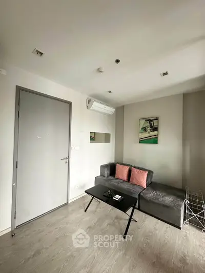 Modern living room with sleek gray sofa, air conditioning, and minimalist decor.