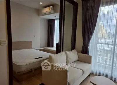 Modern apartment with cozy living room and bedroom, featuring large windows and city view.