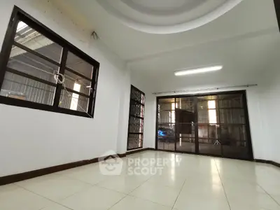 Spacious empty room with large windows and tiled flooring, ideal for customization.