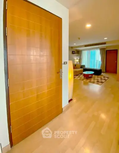 Spacious living room with modern decor and wooden flooring, featuring a cozy seating area and ambient lighting.