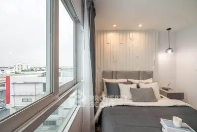 Modern bedroom with large window and stylish decor in urban apartment.