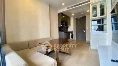 Modern living room with cozy sofa, wooden table, and sleek kitchen area in open layout apartment.