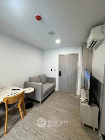 Modern living room with cozy sofa, TV, and dining area in compact apartment.