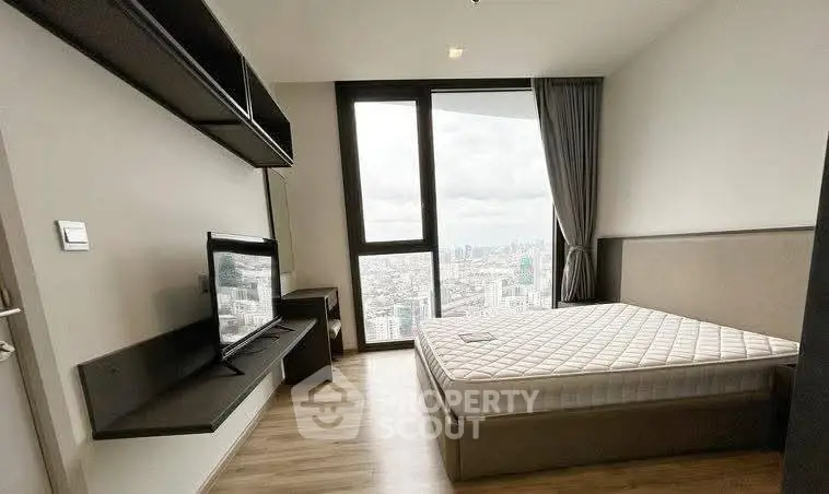 Modern bedroom with city view, featuring a sleek TV setup and large window for natural light.