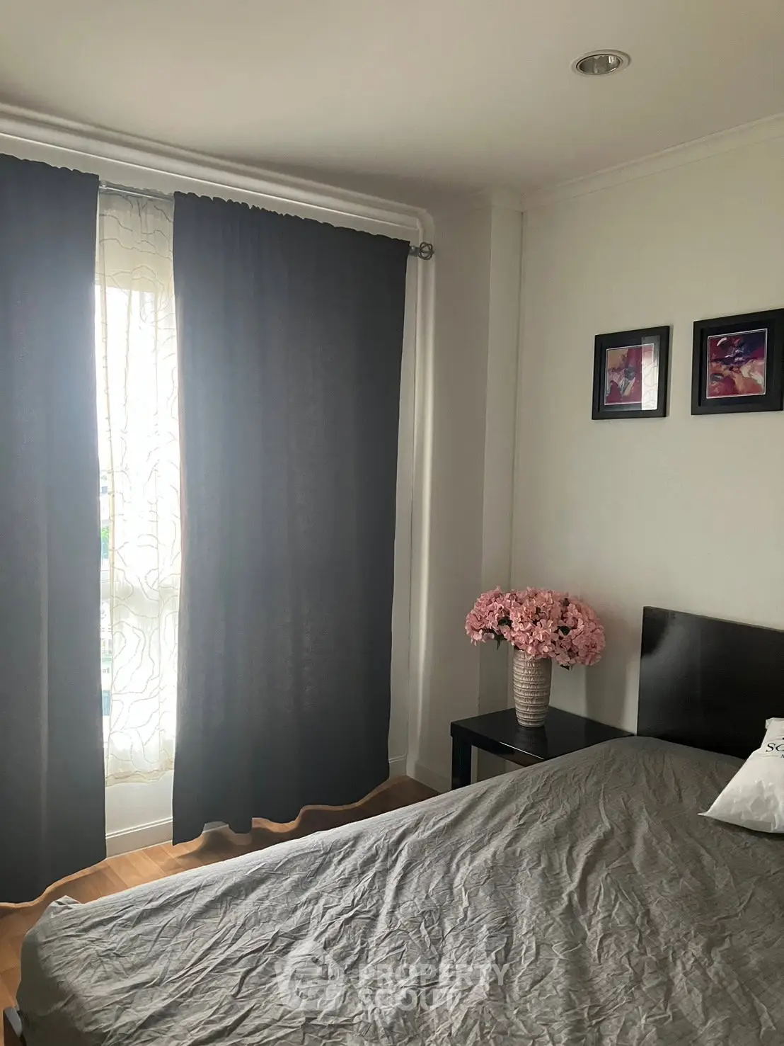Cozy bedroom with elegant decor, featuring a stylish bed, bedside table with flowers, and soft lighting.