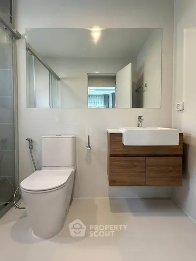 Modern bathroom with sleek fixtures and large mirror in contemporary home.