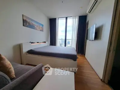 Modern bedroom with city view, featuring sleek furniture and large windows for natural light.