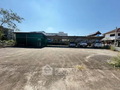 Spacious parking area with multiple cars and a covered structure, ideal for commercial use.