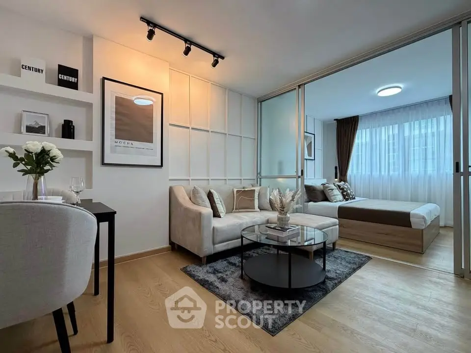 Modern open-plan living room with cozy bedroom, stylish decor, and natural light in a contemporary apartment.