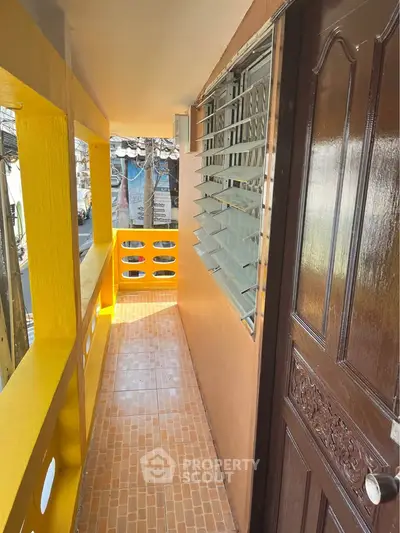 Charming apartment entrance with vibrant yellow balcony and decorative door.