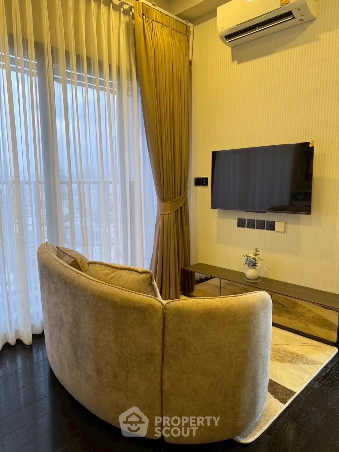 Cozy living room with modern sofa, wall-mounted TV, and elegant curtains.