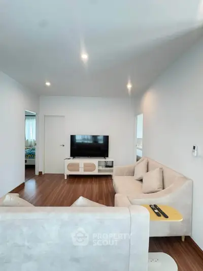 Modern living room with stylish furniture and flat-screen TV, featuring elegant lighting and wooden flooring.