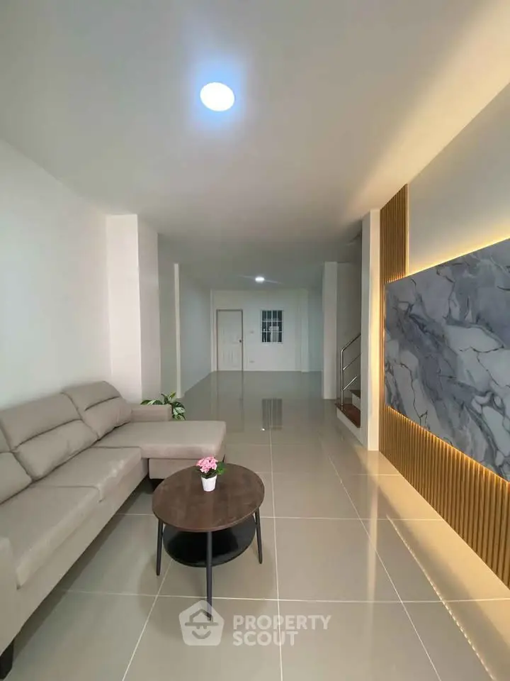 Spacious modern living room with elegant marble accent wall and cozy seating area.