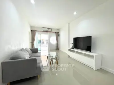 Spacious modern living room with sleek furniture and large TV, perfect for relaxation and entertainment.