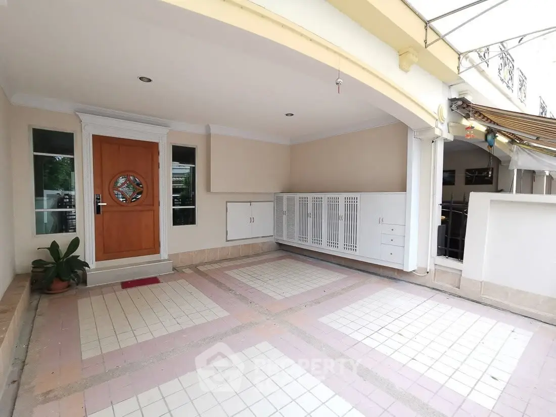 Spacious covered parking area with elegant wooden door and tiled flooring in modern home.