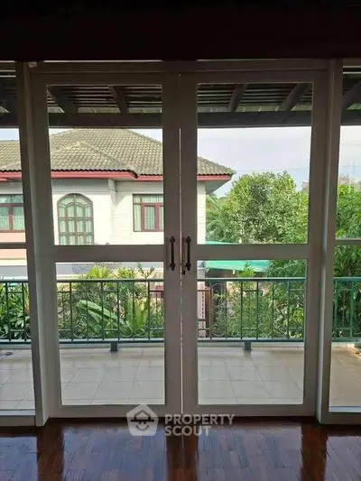 Spacious balcony with elegant glass doors offering a serene garden view, perfect for relaxation.