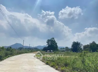 Scenic rural landscape with open road and lush greenery under a bright blue sky.