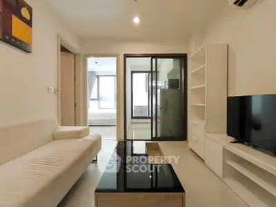 Modern living room with sleek furniture and glass sliding doors leading to a bright bedroom.