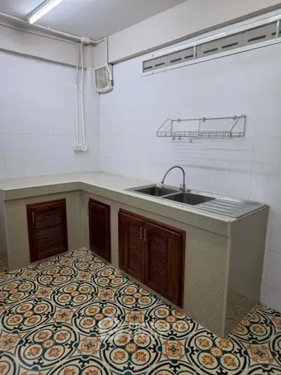 Charming kitchen with vintage patterned floor tiles and modern sink setup.