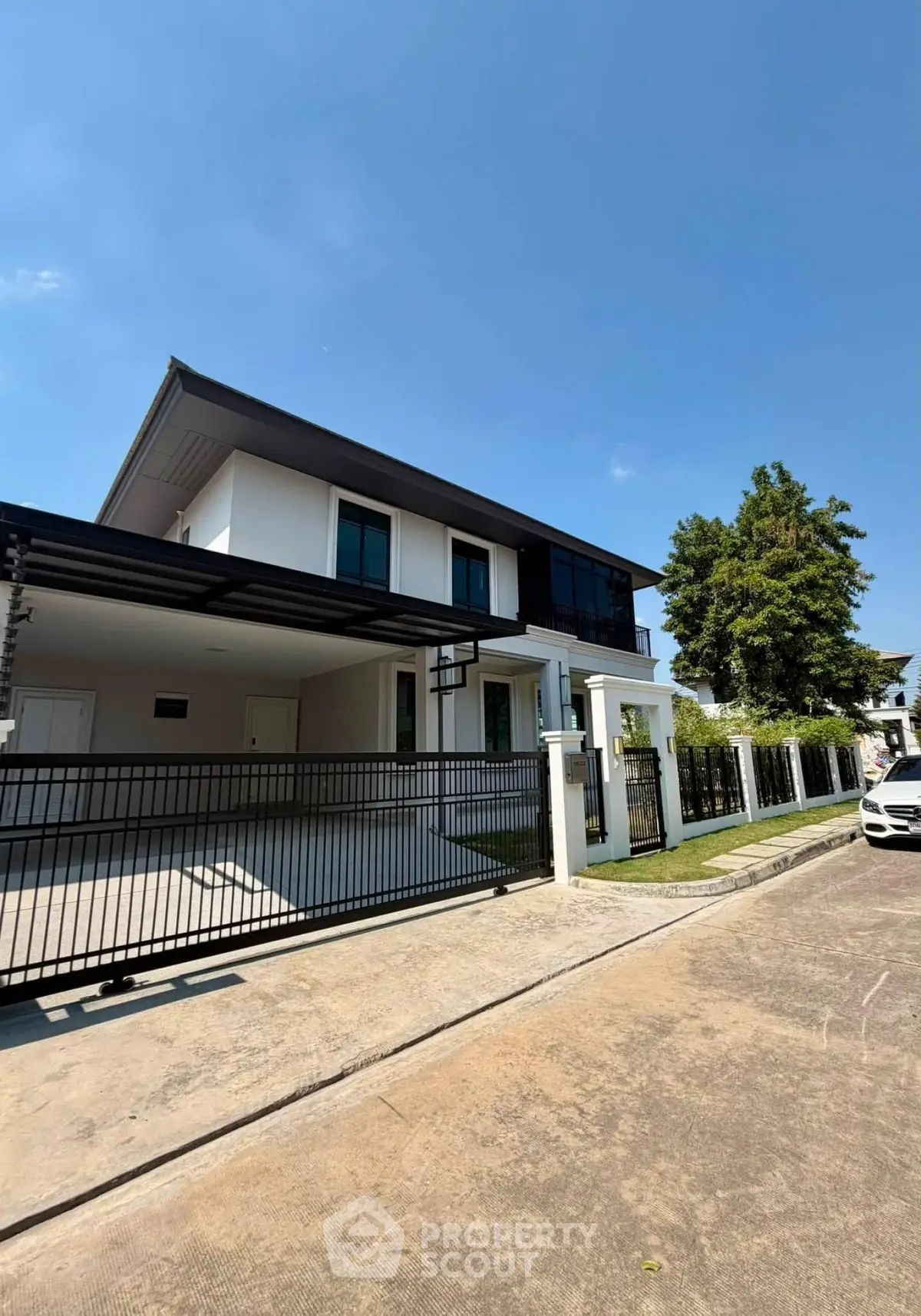 Modern two-story house with sleek design and spacious driveway under clear blue sky.