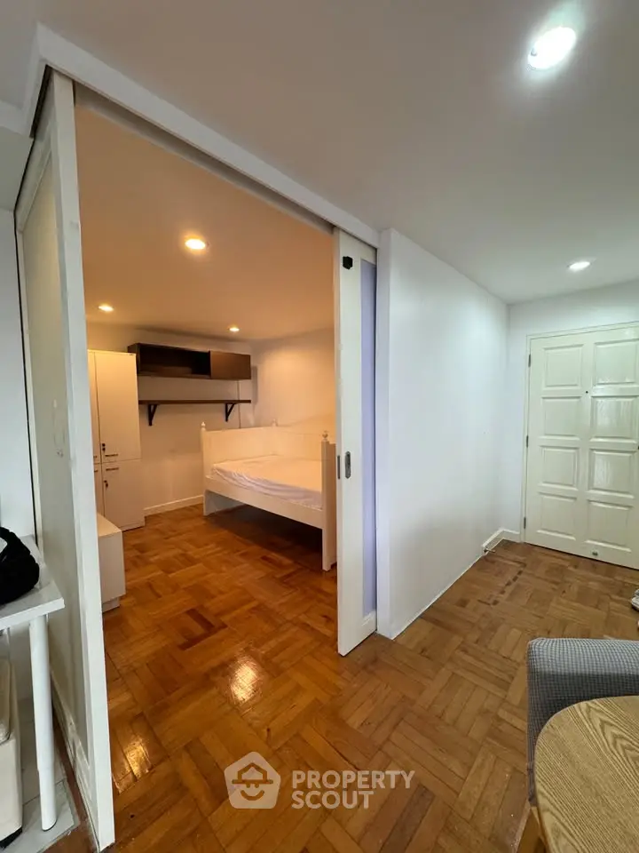 Cozy bedroom with wooden flooring and sliding door in modern apartment