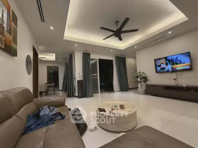 Spacious modern living room with sleek design and cozy ambiance, featuring a large TV and comfortable seating.
