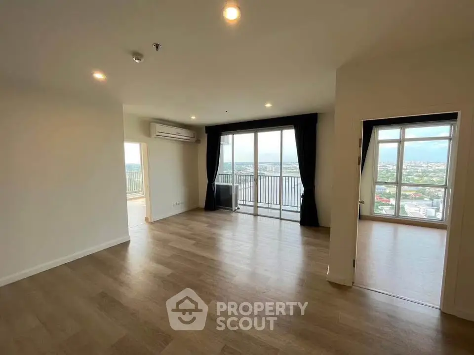 Spacious modern living room with large windows and balcony offering stunning city views.