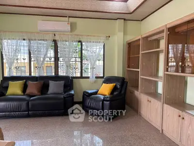 Spacious living room with leather sofas and large windows, perfect for relaxation and entertaining.