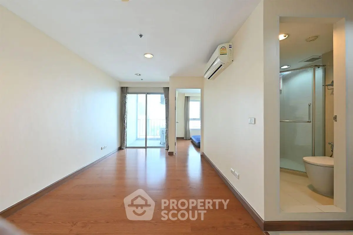 Spacious apartment with wooden flooring, balcony access, and modern bathroom.