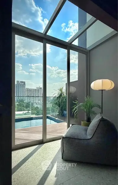 Luxurious living room with floor-to-ceiling windows offering stunning city and pool views.