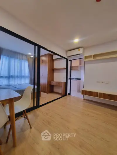 Modern apartment interior with open layout, featuring a cozy dining area and glass partitioned bedroom.