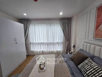 Cozy bedroom with stylish decor and ample natural light from large window.