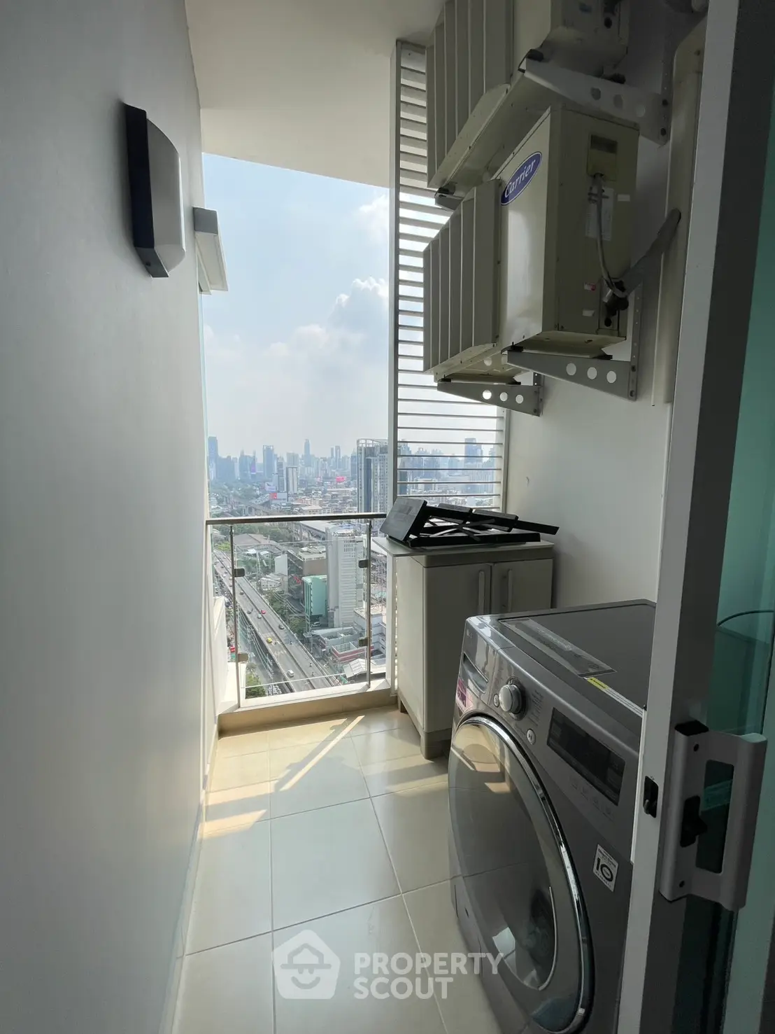 Modern laundry area with city view and washing machine in high-rise apartment.