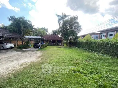 Spacious green garden with carport and charming house in serene neighborhood.