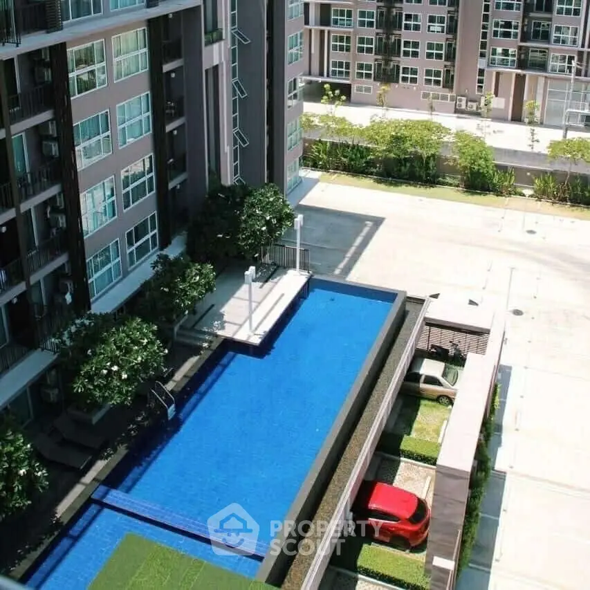 Modern apartment complex with a stunning pool and parking area, offering luxury urban living.