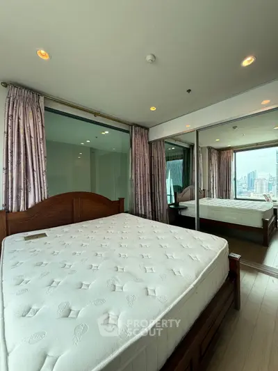 Spacious bedroom with city view and mirrored closet doors