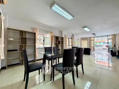 Spacious dining area with modern glass table and elegant chairs, featuring large windows and ample natural light.