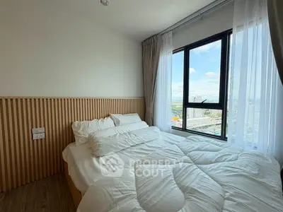 Cozy bedroom with large window offering stunning city views, featuring modern design and natural light.