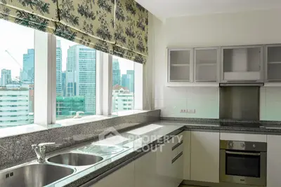 Modern kitchen with city view, featuring sleek countertops and stainless steel appliances.