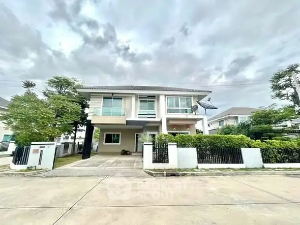 Modern two-story house with lush greenery and spacious driveway in suburban neighborhood.