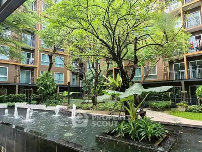 Lush garden courtyard with water feature in modern apartment complex.
