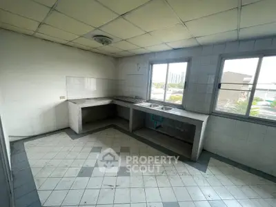 Spacious kitchen with tiled flooring and large windows offering natural light.