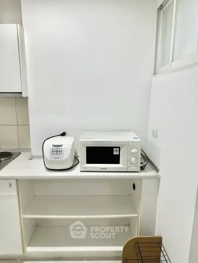 Compact kitchen with microwave and rice cooker on white countertop