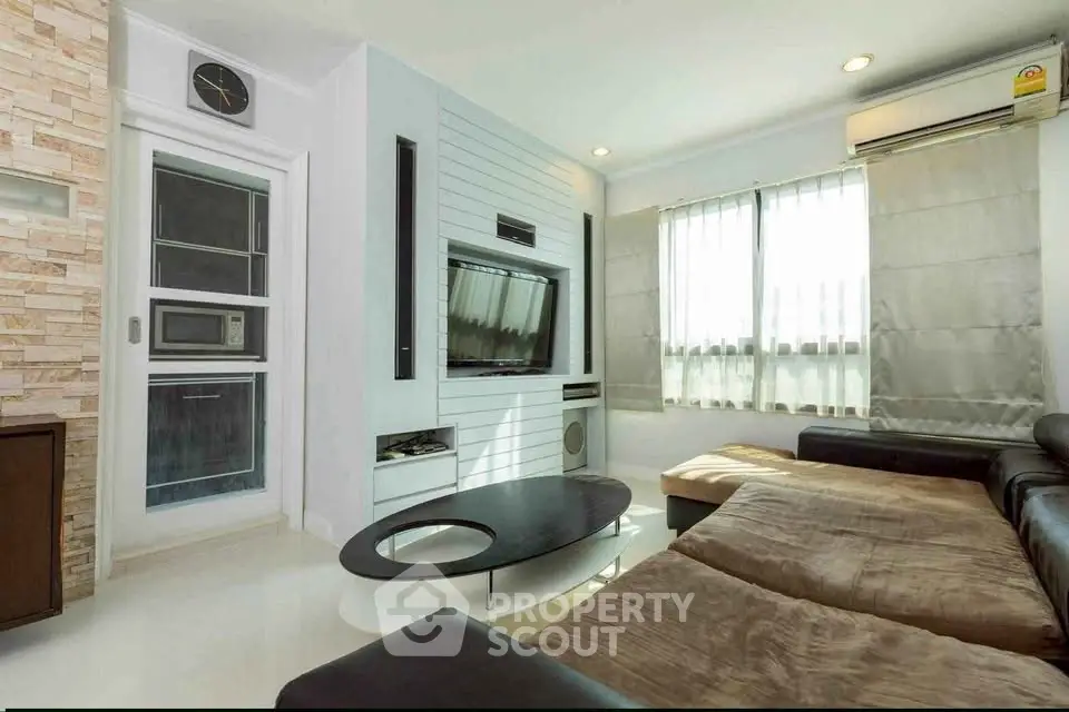 Modern living room with sleek design, large windows, and comfortable seating in a stylish apartment.