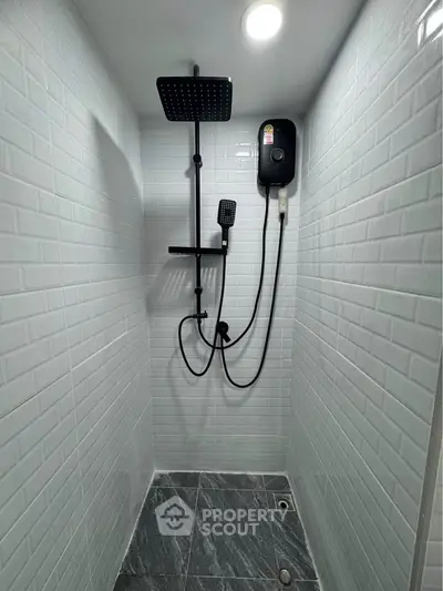 Modern shower area with sleek black fixtures and white subway tiles.